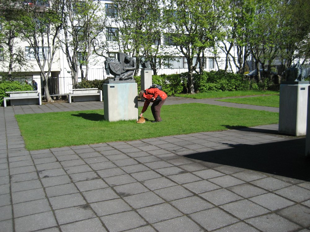 070522_008.jpg - Den skulptur som kvinnan inte ägnar sitt intresse föreställer Heimir, en germansk kung som skyddade sin fosterdotter Aslaug mot de grymma burgunderna genom att gömma henne inne i sin harpa. Han låtsades sedan vara en fattig trubadur och vandrade ända till Norge med barnet i harpan. Där blev han mördad av två män som trodde att det var dyrbarheter han förvarade i instrumentet.   