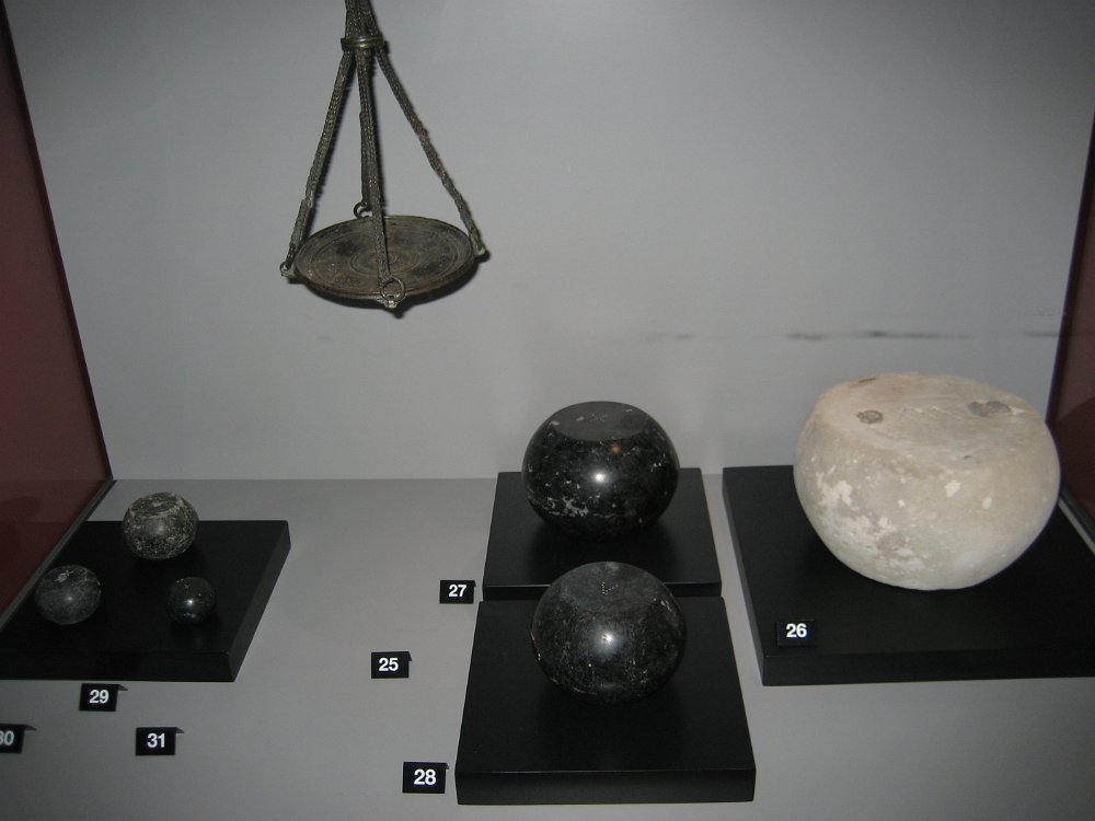 IMG_ 008.jpg - Till vänster och i mitten: Vikter i basalt. I taket: Hävstångsvåg med både krok och vågskål. Man kunde alltså väga varorna antingen i vågskålen eller med krok. Till höger: Vikt i kalksten.   